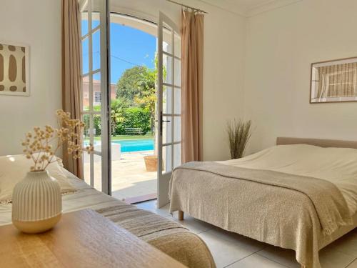 Un dormitorio con una cama y una puerta a una piscina. en Villa avec piscine Domaine des Fées à 100 m plage, en Vaux-sur-Mer