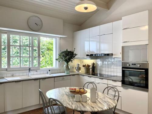 Una cocina con una mesa y un reloj en la pared. en Villa avec piscine Domaine des Fées à 100 m plage, en Vaux-sur-Mer