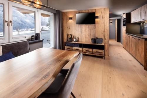 une salle à manger avec une table en bois et une télévision dans l'établissement Schöneben Appartementen Top 1, à Wald im Pinzgau