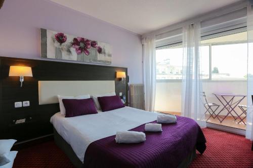 a bedroom with a large bed with two pillows on it at Brit Hotel Bleu Nuit in Saintes