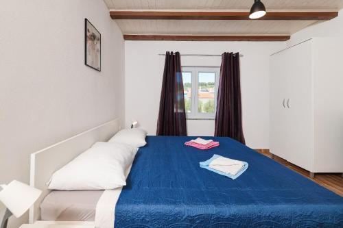 a bedroom with a blue bed with two pillows and a window at Apartments Feliks in Ljubač
