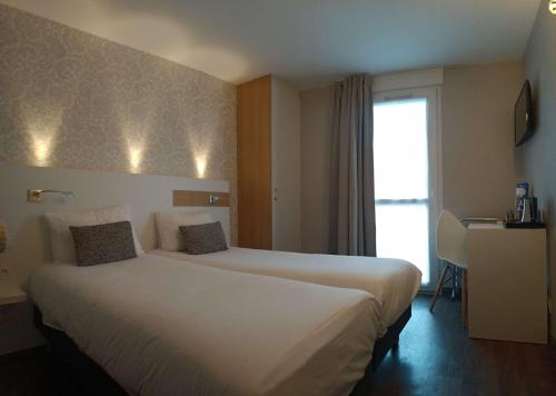 a hotel room with a large bed with a window at Brit Hotel Les Alizes in Pornic