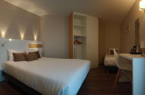 a hotel room with a large bed and a desk at Brit Hotel Les Alizes in Pornic