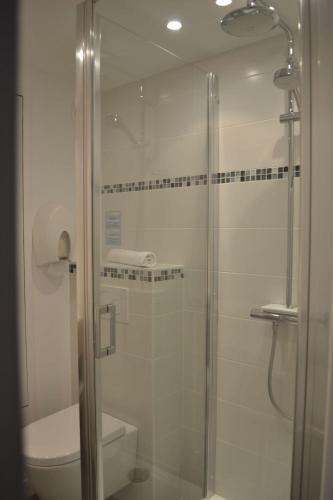 a bathroom with a glass shower with a toilet at Brit Hotel Les Alizes in Pornic