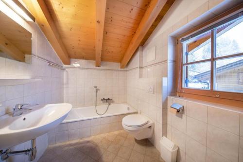 a bathroom with a sink and a toilet and a tub at Schöneben Chalet Holzblick in Wald im Pinzgau