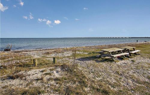 two picnic tables on a beach near the water at Two-Bedroom Holiday Home In Nyborg in Nyborg