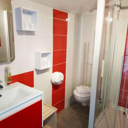 - une salle de bains rouge et blanche avec toilettes et lavabo dans l'établissement Brit Hotel Hermitage, à Royan