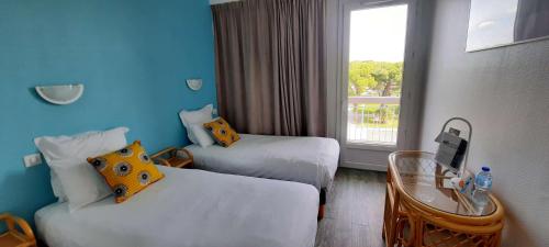 a hotel room with two beds and a window at Brit Hotel Hermitage in Royan