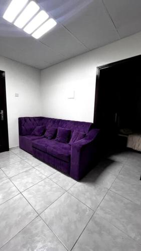 a purple couch in a white room with a ceiling at Affordable Cozy 1 Bedroom in Ajman 