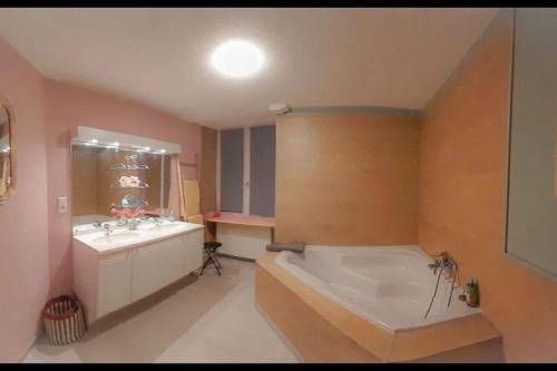 une grande salle de bain avec une baignoire et un lavabo dans l'établissement Suite Jeux Coquins La Curieuse, à Villersexel