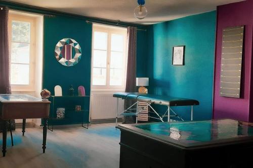 une chambre avec une table et un mur bleu dans l'établissement Suite Jeux Coquins La Curieuse, à Villersexel