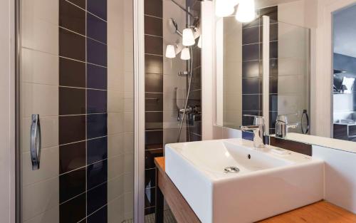 a bathroom with a white sink and a shower at Brit Hotel de Paris Saint-Jean-de-Luz in Saint-Jean-de-Luz