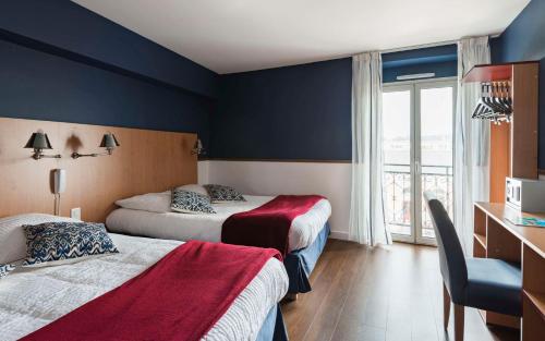 a hotel room with two beds and a window at Brit Hotel de Paris Saint-Jean-de-Luz in Saint-Jean-de-Luz