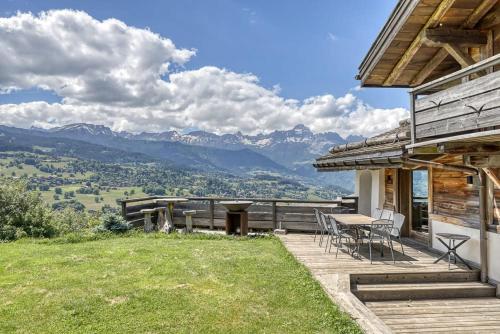 une maison avec une terrasse avec une table et des chaises dans l'établissement Chalet Carline, à Combloux