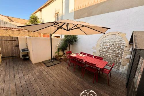a patio with a table and an umbrella at Maison Ferry - Welkeys in Rivedoux-Plage