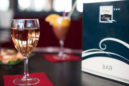 a glass of wine sitting on a table next to a book at Brit Hôtel De L'océan in Concarneau