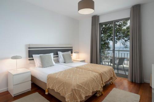 a bedroom with a large bed and a balcony at Apartamento Princesa Dona Amélia by An Island Apart in Funchal