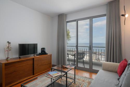 a living room with a television and a balcony at Apartamento Princesa Dona Amélia by An Island Apart in Funchal