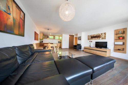 a living room with a black leather couch at Schöneben Haus Arnika in Wald im Pinzgau