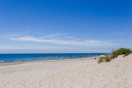 a sandy beach with a view of the ocean at Chez Misha - Sublime maison climatisée à 100m des plages de Carnon in Mauguio