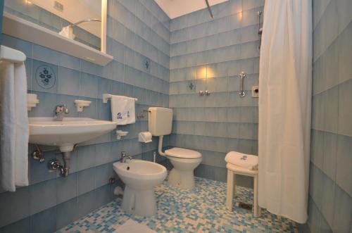 a bathroom with two toilets and a sink and a toilet istg at Aparthotel Pineda in Bibione