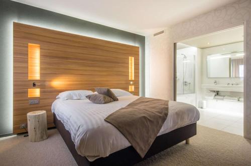 a bedroom with a large bed with a wooden headboard at Brit Hotel & Spa Saint Brieuc Plérin in Plérin