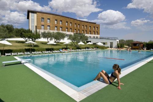 una mujer sentada en el borde de una piscina en Grand Hotel Garden en Barile