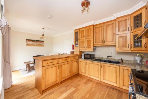 a kitchen with wooden cabinets and a wooden floor at Beautiful 5-Bed Villa in Waterford in Waterford