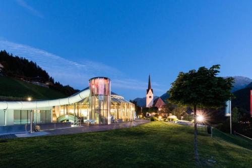 a large glass building with a church in the background at Schöneben Haus Sonneck in Wald im Pinzgau