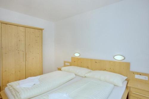 a bedroom with two white beds and a wooden cabinet at Schöneben Haus Sonneck in Wald im Pinzgau