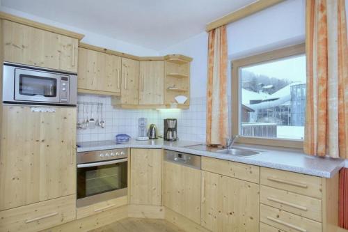 a kitchen with wooden cabinets and a window at Schöneben Haus Sonneck in Wald im Pinzgau
