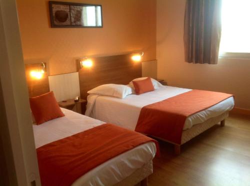 a hotel room with two beds and a window at Brit Hotel Magdalena in Varennes Vauzelles