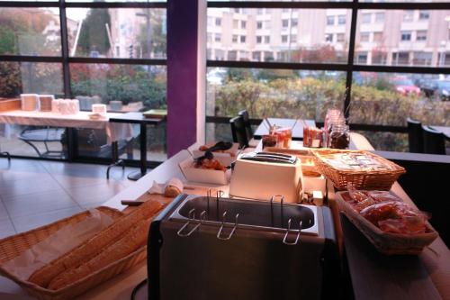 a kitchen with a counter with food on it at Brit Hotel Confort Rouen Centre in Rouen
