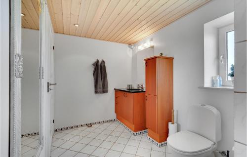 a bathroom with a toilet and a wooden cabinet at 3 Bedroom Beautiful Apartment In Kibæk in Kibæk