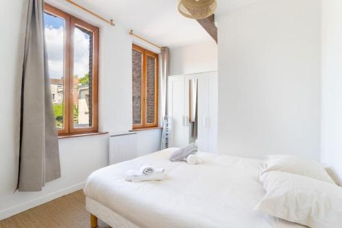 une chambre blanche avec un lit avec des serviettes dessus dans l'établissement Appartement spacieux et fonctionnel - centre, à Douai