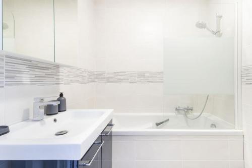 une salle de bain blanche avec une baignoire et un lavabo dans l'établissement Appartement spacieux et fonctionnel - centre, à Douai
