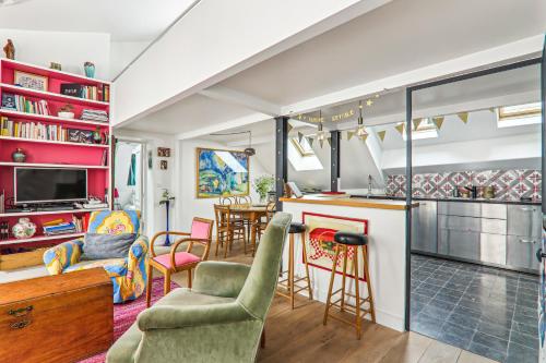 Il comprend une cuisine et un salon avec un bar et des chaises. dans l'établissement Cosy apartment Place des Vosges, à Paris