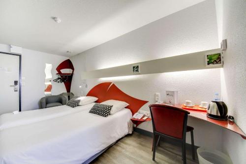 a hotel room with a bed and a desk at Brit Hotel Porte d'Espagne in Perpignan