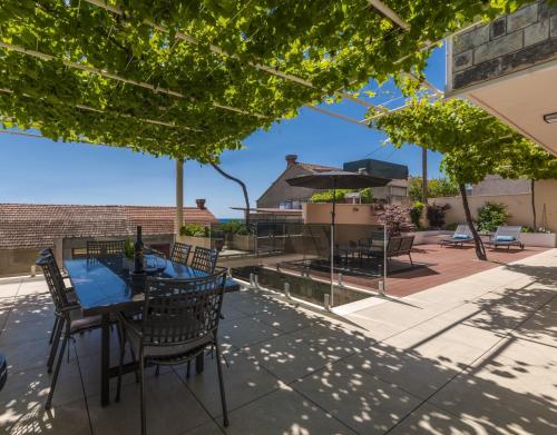 eine Terrasse mit einem Tisch, Stühlen und Bäumen in der Unterkunft Hillside Apartments in Dubrovnik