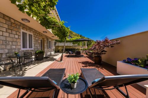 eine Terrasse mit Stühlen und Tischen auf einer Holzterrasse in der Unterkunft Hillside Apartments in Dubrovnik