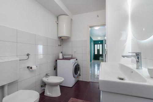 a white bathroom with a toilet and a sink at Villa Alina with heated pool in Rogoznica