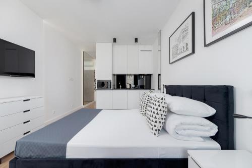 a bedroom with a bed with pillows and a tv at Selenite - Studio with Balcony & AC - City Center in Krakow