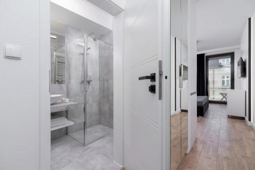 a white bathroom with a shower and a sink at Selenite - Studio with Balcony & AC - City Center in Krakow