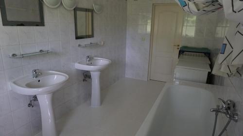 a white bathroom with two sinks and a bath tub at Pensjonat Kowalski in Łubowo