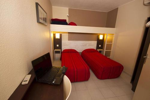 a room with a laptop computer on a desk with two beds at Brit Hotel Essentiel Sète / Balaruc in Balaruc-le-Vieux