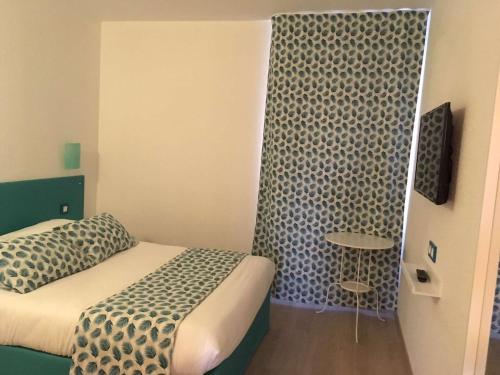 a small room with a bed and a table at Brit Hotel Salon de Provence in Salon-de-Provence
