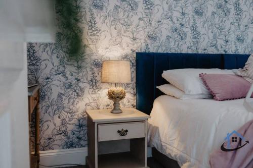 a bedroom with a bed and a table with a lamp at Indigo Snug - Gorgeous 2 bed flat in the heart of Cromer in Cromer