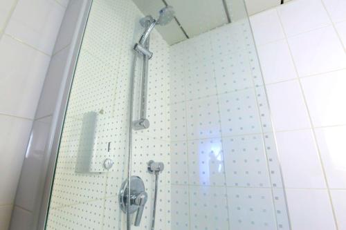 a shower in a bathroom with white tiles at Brit Hotel Calais in Calais