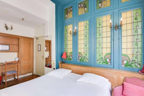 a bedroom with a bed and stained glass windows at Brit Hotel Notre Dame in Valenciennes