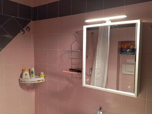 a bathroom with a mirror and a pink tiled wall at Casina di Adele apartment in Volterra